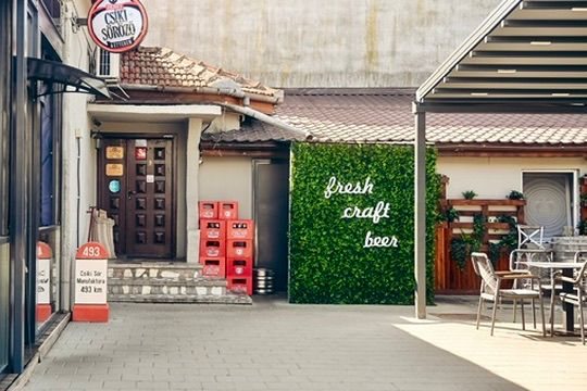 Intrarea în local, cu perete verde și inscripția fresh craft beer