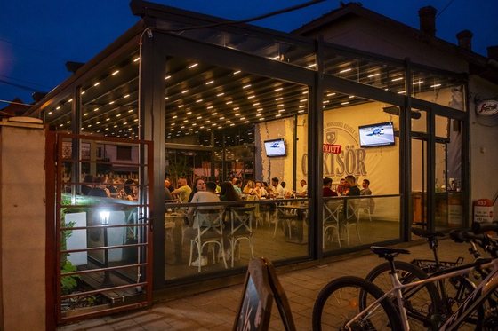 Terasa acoperită văzută din exterior, iluminată seara